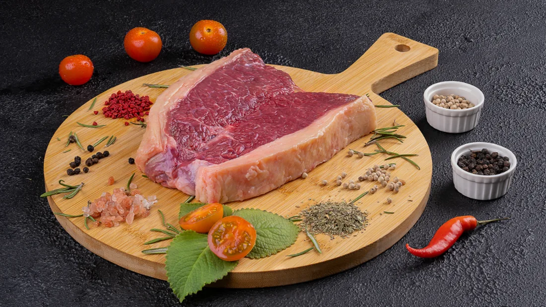 Fotografía gastronómica: corte de carne crudo sobre tabla con especias